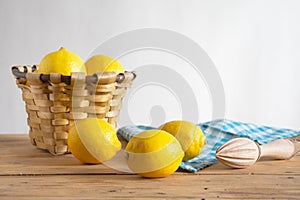 View of rustic table with basket with lemons, cloth and wooden juicer, white background, horizontal,