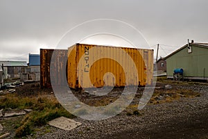 View of rusty containers in a field under the cloudy sky