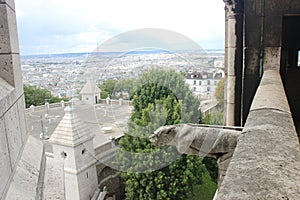 View from SacrÃ© Coeur onto the roofs of Paris, a stone gargoyle and the Eiffel tower