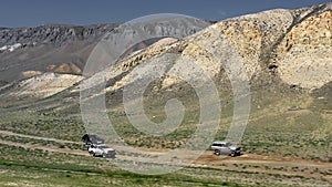 View of safari vehicle driving on sand tracks road. Aerial over off road 4x4 car driving along gravel trail path near