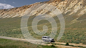 View of safari vehicle driving on sand tracks road. Aerial over off road 4x4 car driving along gravel trail path near