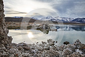 View of a Saline Soda Lake with Snow Capped Eastern Sierra Navada Mountains on a Cloudy Day in the Afternoon with Sunlight Shinnin photo