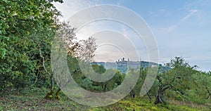 View of San Gimignano, Tuscany, between sky and trees of olive during sunset