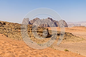 A view from a sand dune towards rocky outcrops in the desert landscape in Wadi Rum, Jordan