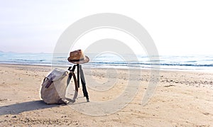 View of the sandy beach with a brown hat and knapsack on the beach near the sea.