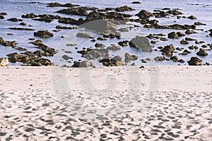 View of sandy beach at low tide revealing rocks on the ocean