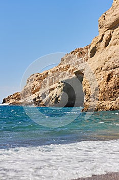 View of sandy beach, sealine, waves, cliff and blue sky in the summer sunny day