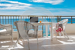 View of the sea from balcony with white table and cheas, blue sk