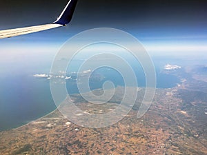 View of the sea on the coastal strip from the height of the flight of a passenger plane. Part of the wing is in the frame