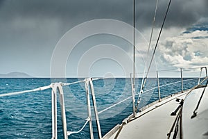 The view of the sea and mountains from the sailboat, edge of a board of the boat, slings and ropes, splashes from under