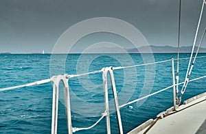 The view of the sea and mountains from the sailboat, edge of a board of the boat, slings and ropes, splashes from under