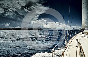 The view of the sea and mountains from the sailboat, edge of a board of the boat, slings and ropes, splashes from under