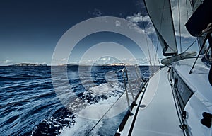 The view of the sea and mountains from the sailboat, edge of a board of the boat, slings and ropes, splashes from under