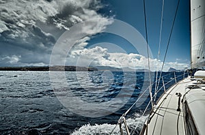 The view of the sea and mountains from the sailboat, edge of a board of the boat, slings and ropes, splashes from under