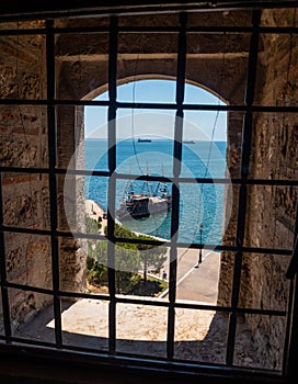 View of the sea and the ships through the bars on the window in the White Tower in Thessaloniki, Greece