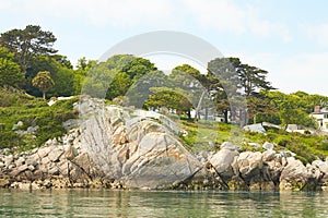 View from the sea to the greeny cliffs with exotic trees, moss and blue sky.