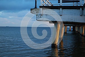 View of the sea water under the pier. Columns of the pier. Pier on the sea. Waves on the water of the sea. Close-up of the pier.