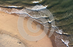 View of sea waves and gulls wandering along Tenby South Beach at tide, Wales, United Kingdom