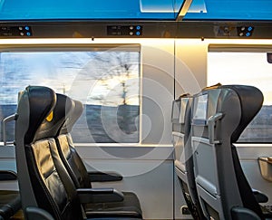 View of seats driving train with landscape outside the window. Screens and comfortable travel