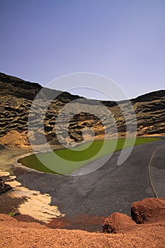 View on secluded deep green lake Lago verde in lagoon surrounded by impressive cliffs - El Golfo, Lanzarote