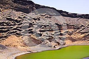 View on secluded deep green lake Lago verde in lagoon surrounded by impressive cliffs - El Golfo, Lanzarote