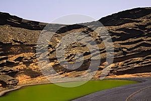 View on secluded deep green lake Lago verde in lagoon surrounded by impressive cliffs - El Golfo, Lanzarote