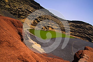 View on secluded deep green lake Lago verde in lagoon surrounded by impressive cliffs - El Golfo, Lanzarote