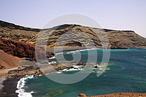 View on secluded lagoon surrounded by impressive rugged weathered cliffs in different colors - El Golfo, Lanzarote