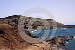 View on secluded lagoon surrounded by impressive rugged weathered cliffs in different colors - El Golfo, Lanzarote