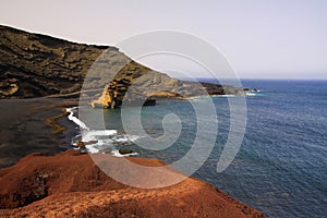 View on secluded lagoon surrounded by impressive rugged weathered cliffs in different colors - El Golfo, Lanzarote