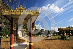 View on secluded  valley with over 1000 sitting buddha statues in rows contrasting with blue sky