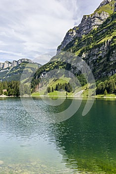 The view of the Seealpsee lake in Appenzell, Switzerland sitting betweeen the tall peaks of the Alpstein mountain range