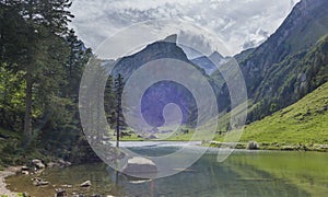 The view of the Seealpsee lake in Appenzell, Switzerland sitting betweeen the tall peaks of the Alpstein mountain range photo