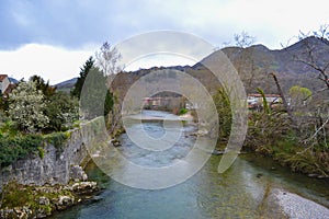 View of the Sella river in Cangas de Onis, Asturias, Spain, between trees and with a small town at the background