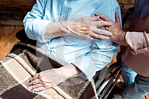 View of senior disabled man holding hands with wife