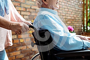 View of senior disabled man sitting in wheelchair near wife