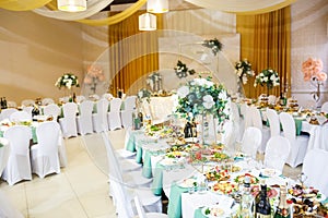 View of the served for decorated wedding dinner table in elite restaurant with beautiful flowers