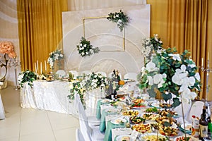 View of the served for decorated wedding dinner table in elite restaurant with beautiful flowers