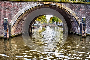 View of seven centuries old bridges in a straight line over the Reguliersgracht, viewed from a canal boat in Amsterdam