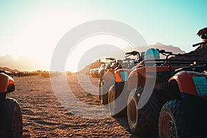 View of several atv quad bikes parked inline in the middle of a desert near hurghada. Sunset hour with the sun shining straight at