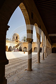 View from shaded archway onto courtyard of Great Mosque of Sousse with domed tower photo