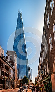 View of The SHARD - the modern skyscraper with its futuristic glass arrow spire facade form emerging between downtown buildings