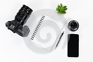 View of shcool supplies with a camera and smarphone, a plant and lenses on white bcakground