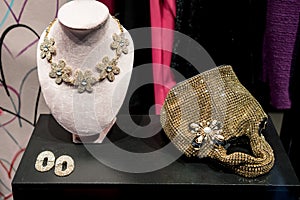 View through the shop window: gold sequin handbag, a gold statement necklace and gold earrings photo