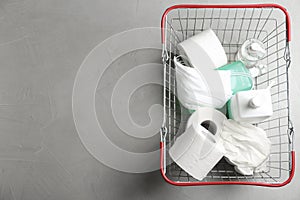 View of shopping basket with antiseptics, toilet paper, gloves and masks on light grey stone table, space for text. Panic