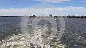 View of the shore and ocean from the stern of the ship.View of the waves following the ship in sunny weather.