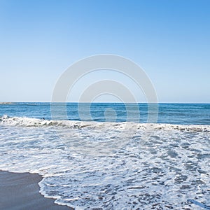 View of from the shore of on a restless sea with of white foam with sunny sky. Summer paradise beach in Spain. Summer seascape.