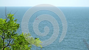 View from the shore to the boat under sail, which floats in the sea