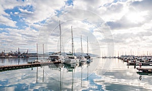 View from the shore to the sea harbor with moored ships under thick clouds with a blue sky peeking through them