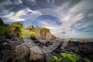 View from a shoreline on Dunluce Castle nested on the edge of cliff, Northern Ireland